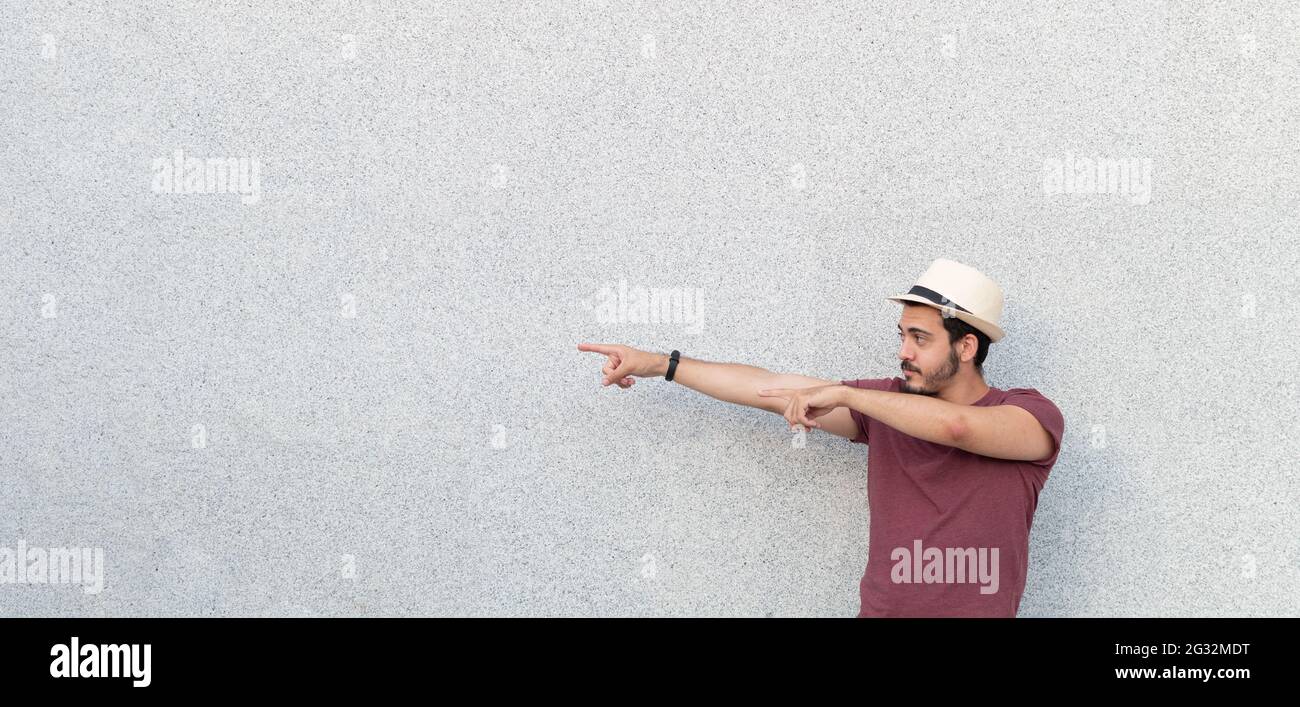 Young man wearing a hat while pointing to the side of a copy space area. Stock Photo