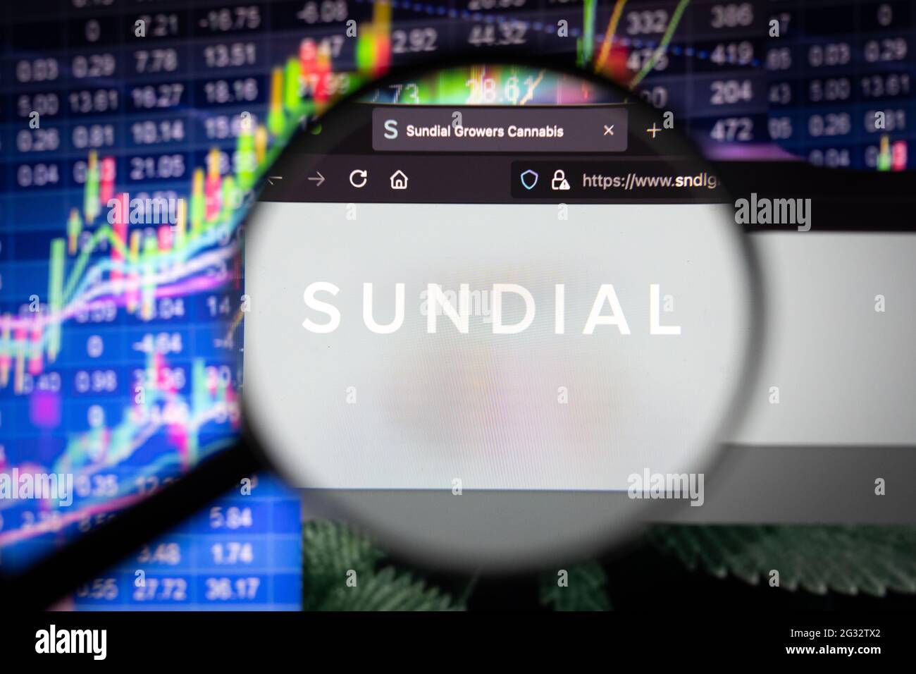 Sundial  company logo on a website with blurry stock market developments in the background, seen on a computer screen through a magnifying glass Stock Photo