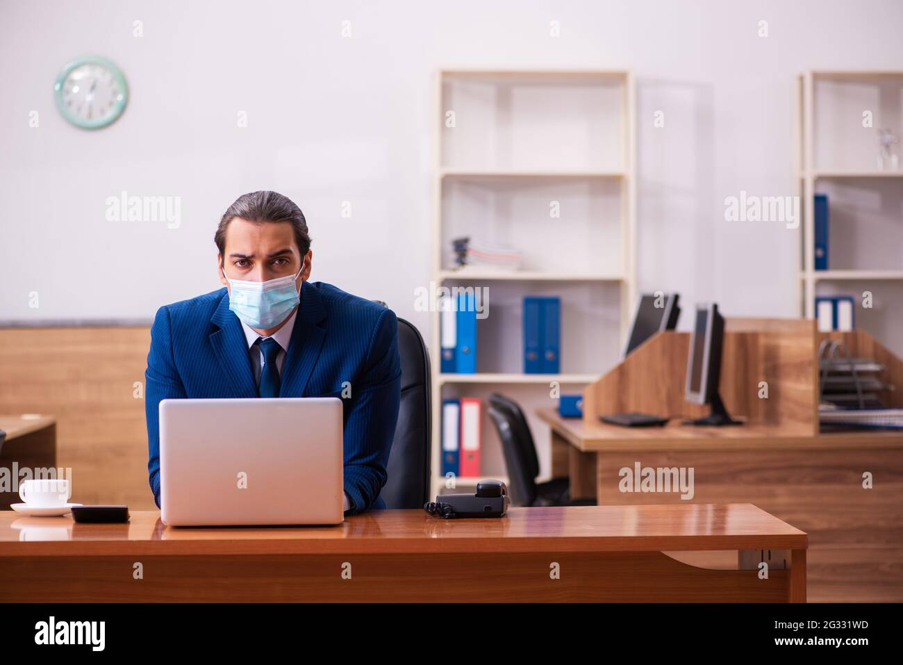 Young employee working in the office wearing mask Stock Photo - Alamy