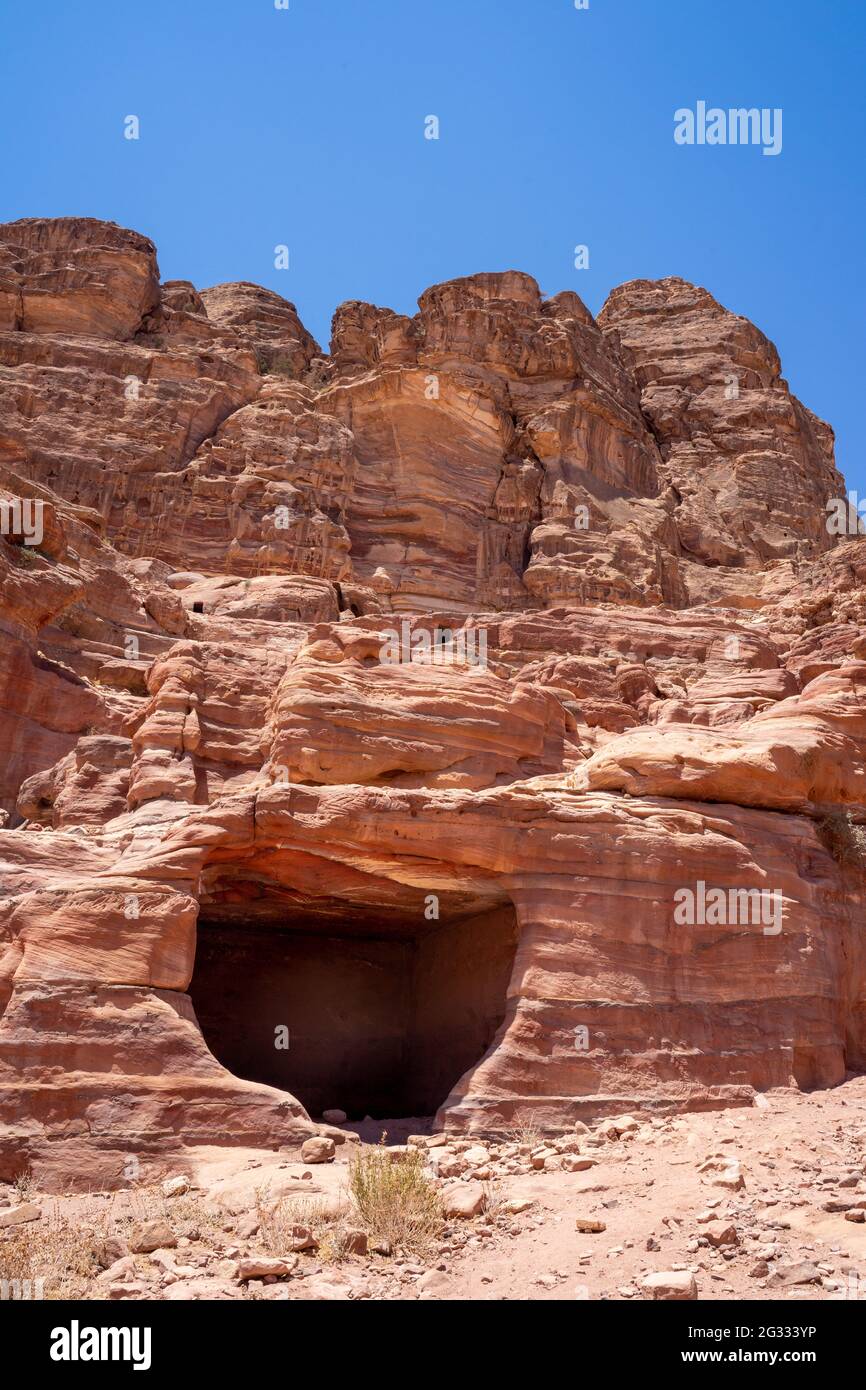 Carved cave in multicolored redrose sandstone with signs of weathering and erosion, patterns