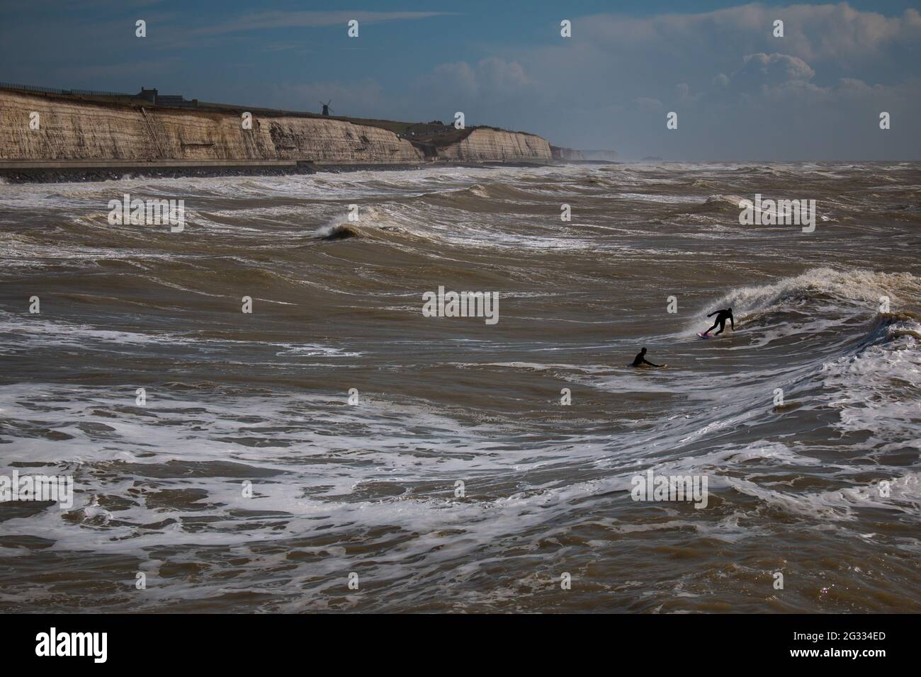 Tiny figures of surfers near the Undercliff walk of Brighton, UK Stock Photo