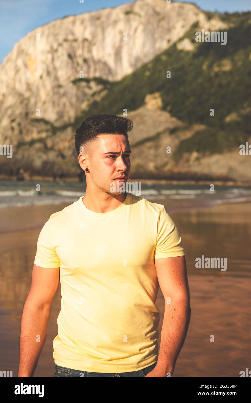 Young caucasian man walking at the beach Stock Photo