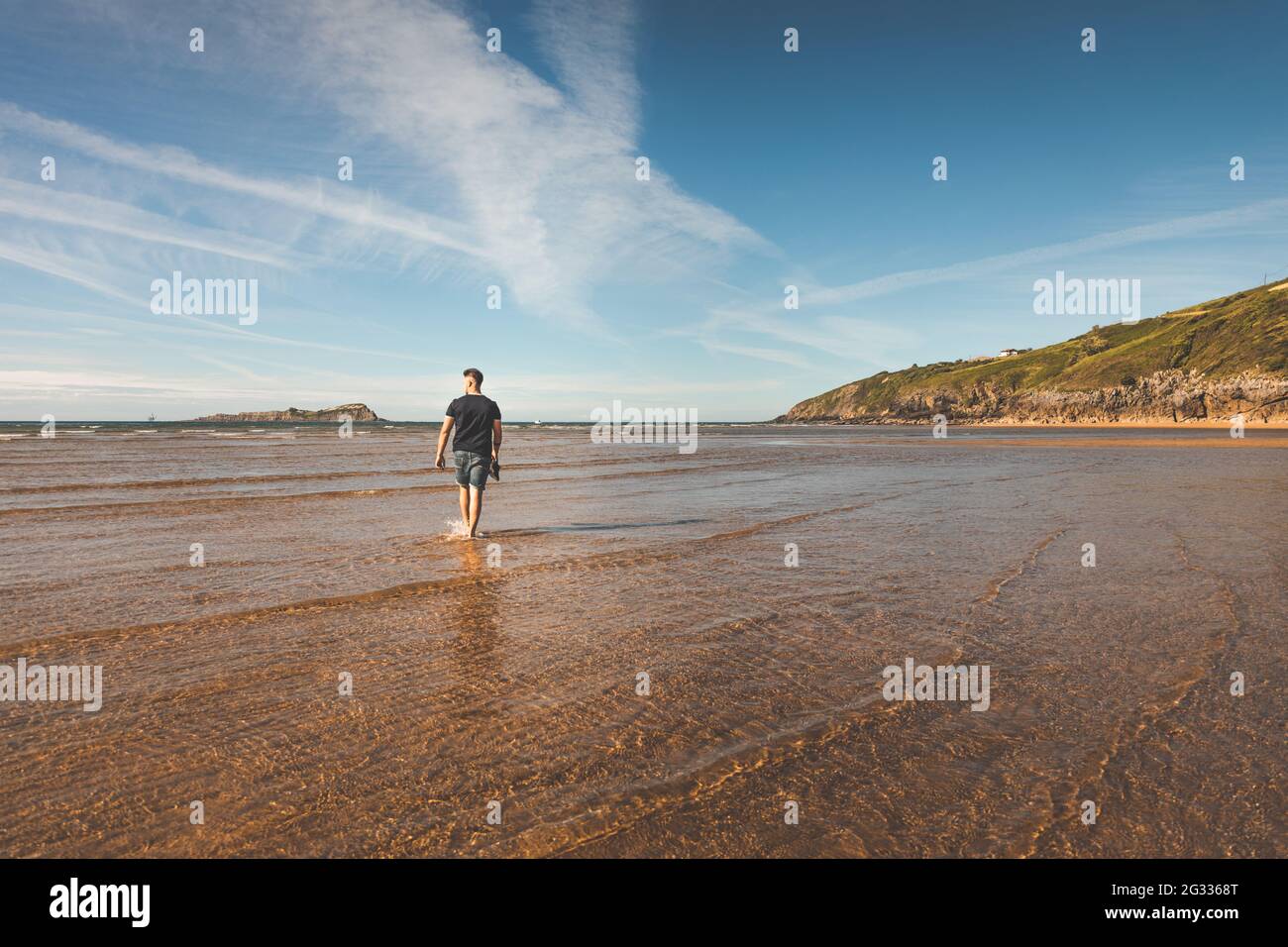 Young caucasian man walking at the beach Stock Photo