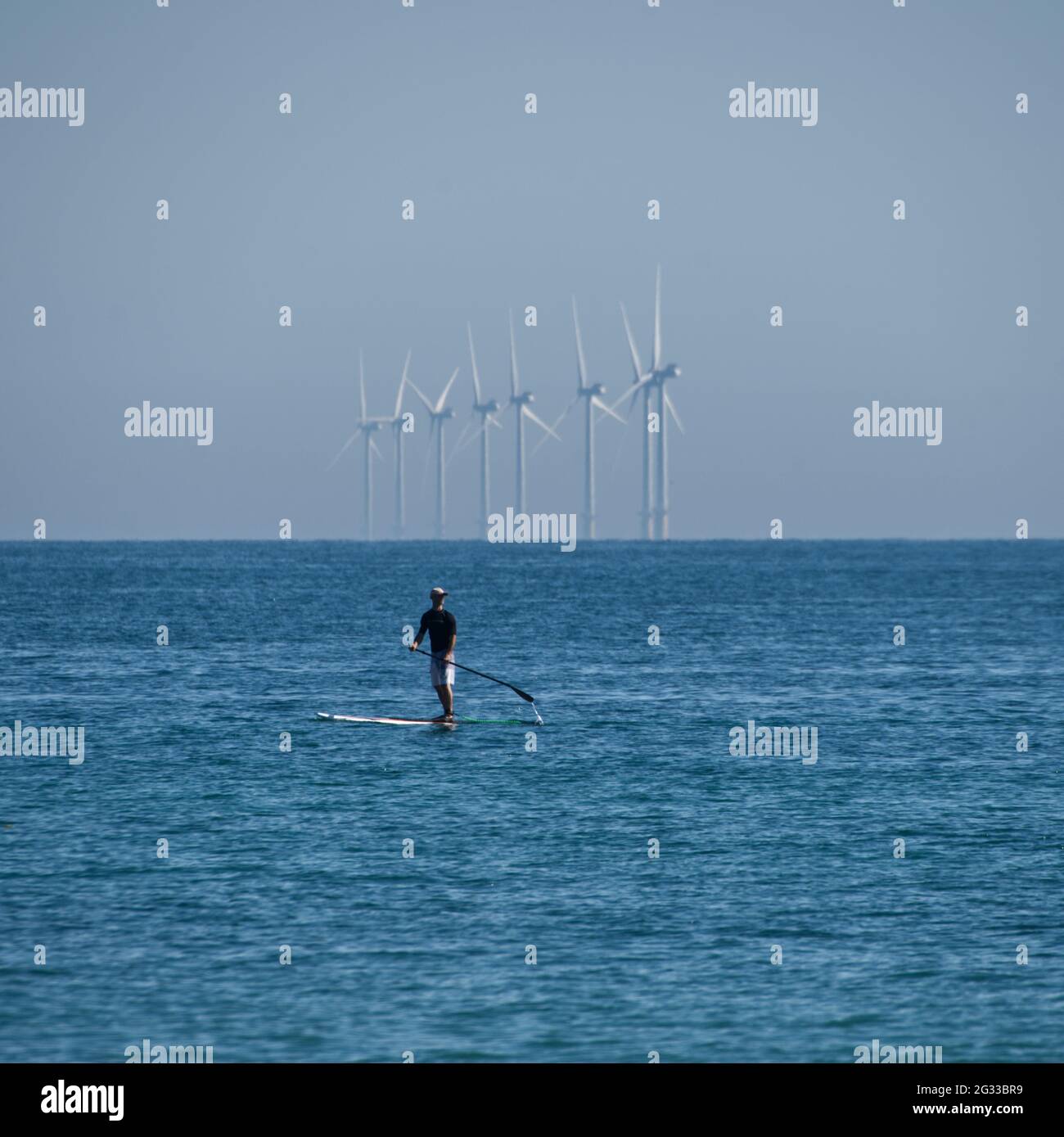 Paddle board by wind turbines Stock Photo Alamy