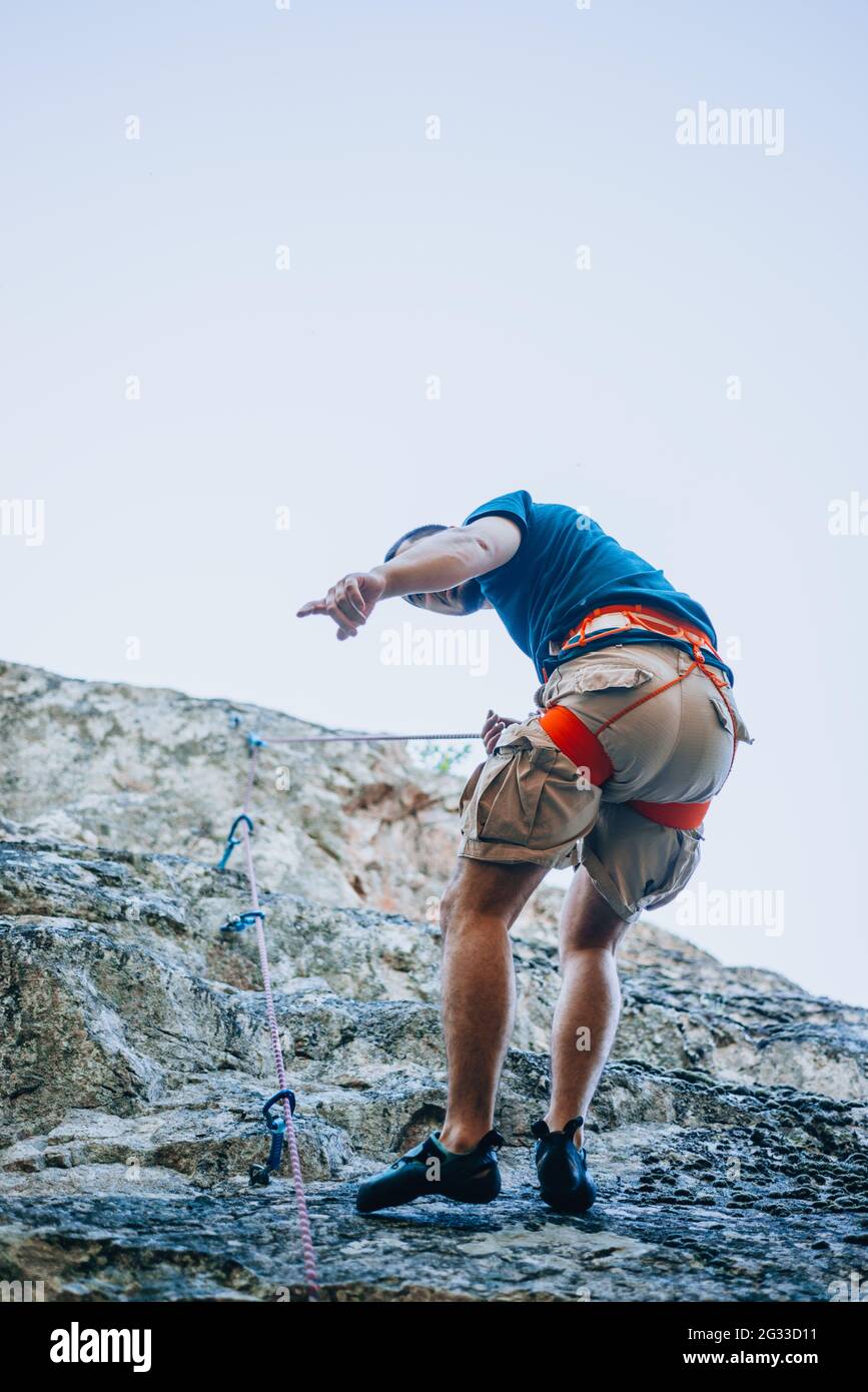 A rockclimber finding a foothold on the steep mountain he's climbing