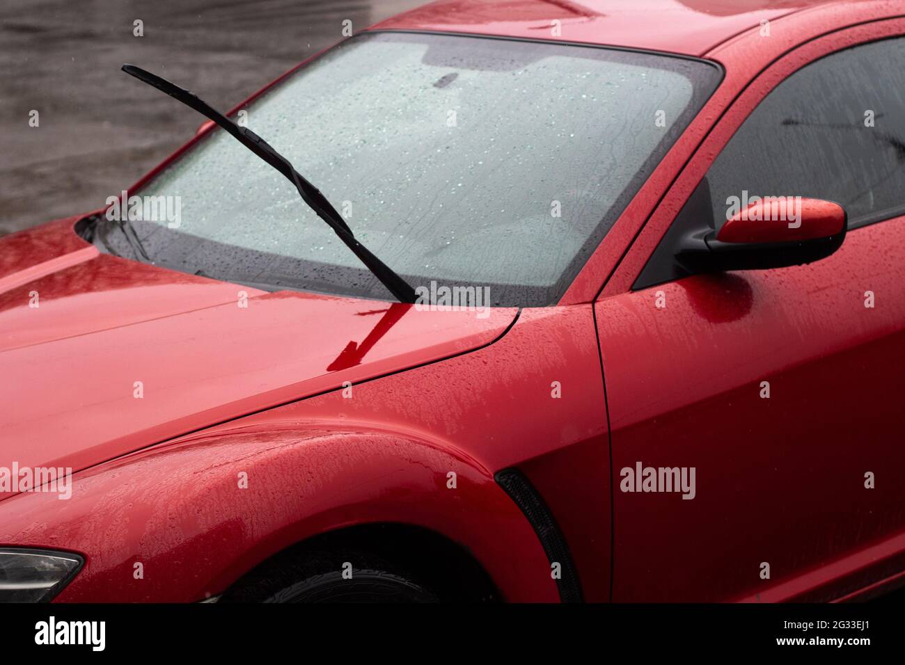 Red car in the parking lot. Car surface. Wet car after rain. Details of