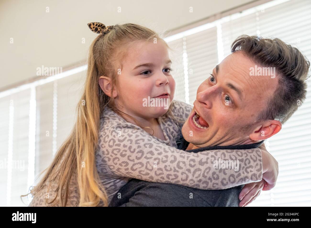 Man playfully holding his happy 4 year old daughter.  (MR) Stock Photo