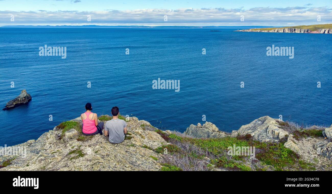 Two hikers take in the views from the top of a cliff on the shoreline hiking trail near Bay Roberts, Newfoundland. Stock Photo