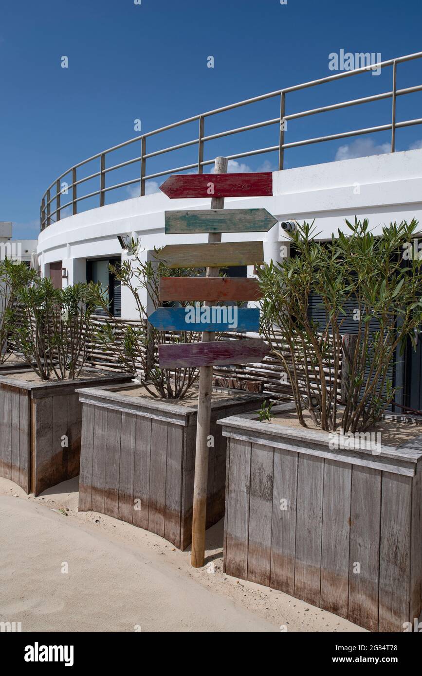 Direction signs on a beach in front of a building Stock Photo