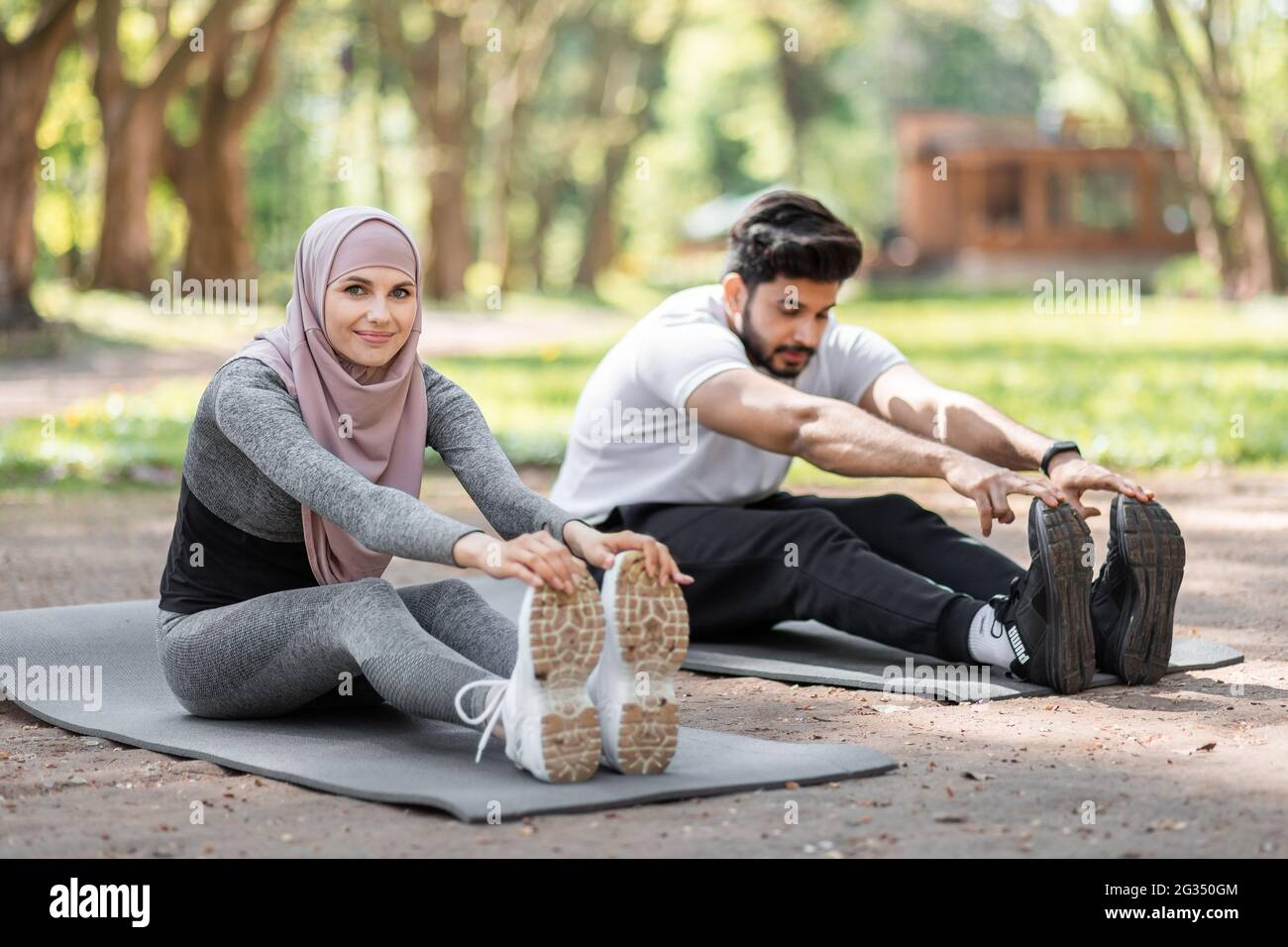 Active muslim couple in sport clothes sitting on yoga mat and