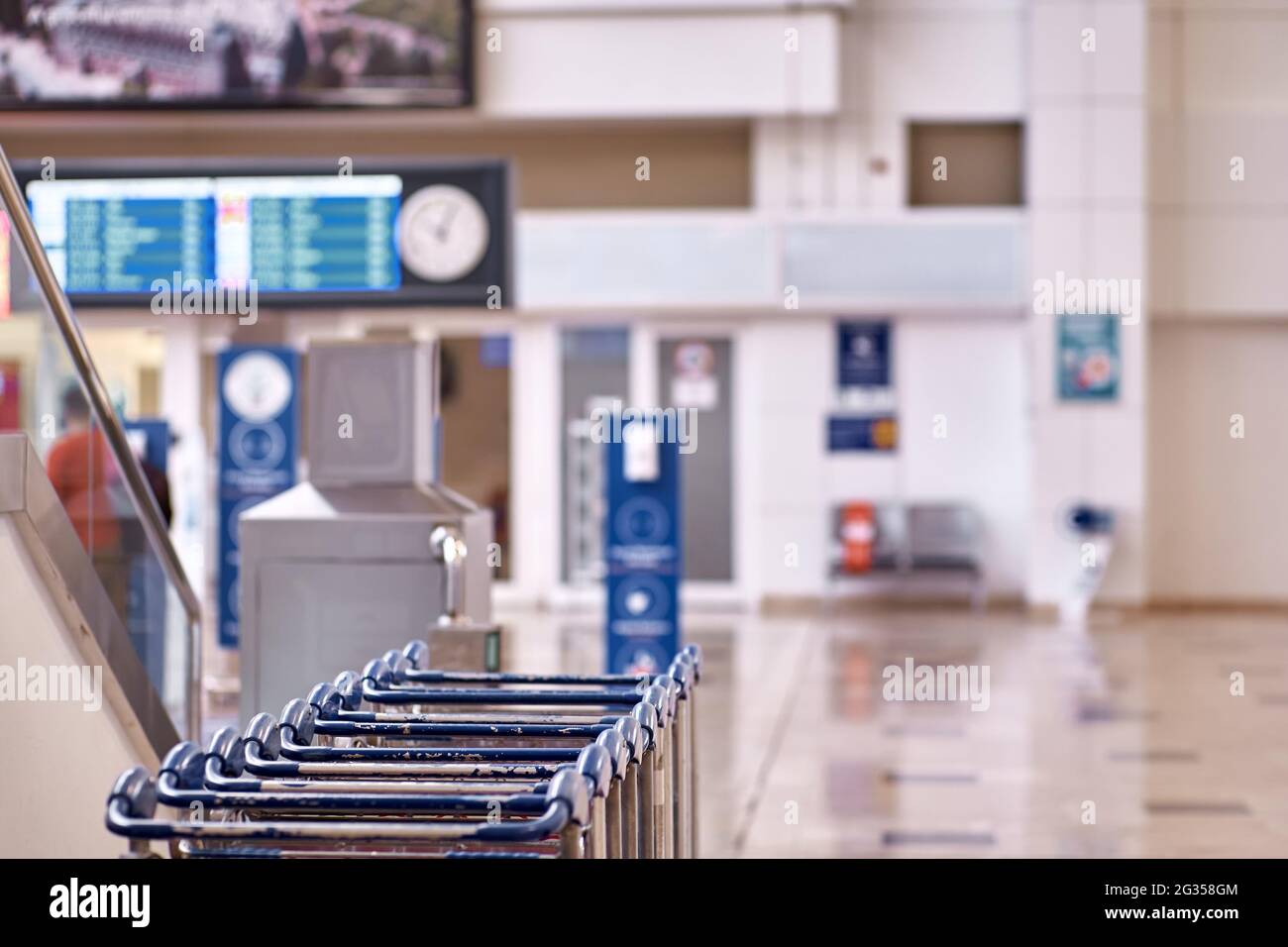 Airport luggage trolleys, flight schedules and wall clocks with copy space. Selective focus. High quality photo Stock Photo