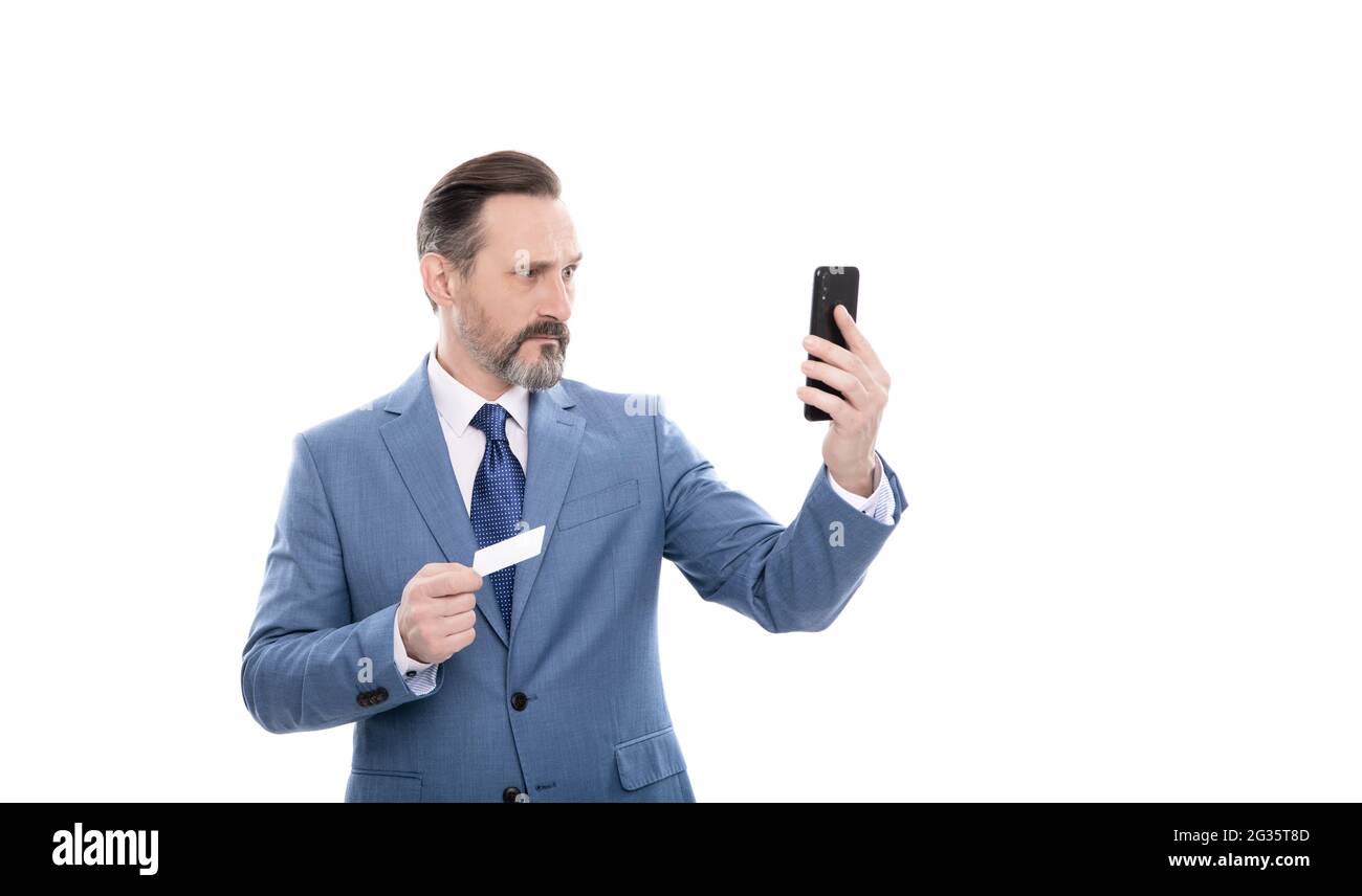 serious mature boss in suit hold credit card and phone isolated on white, selfie Stock Photo