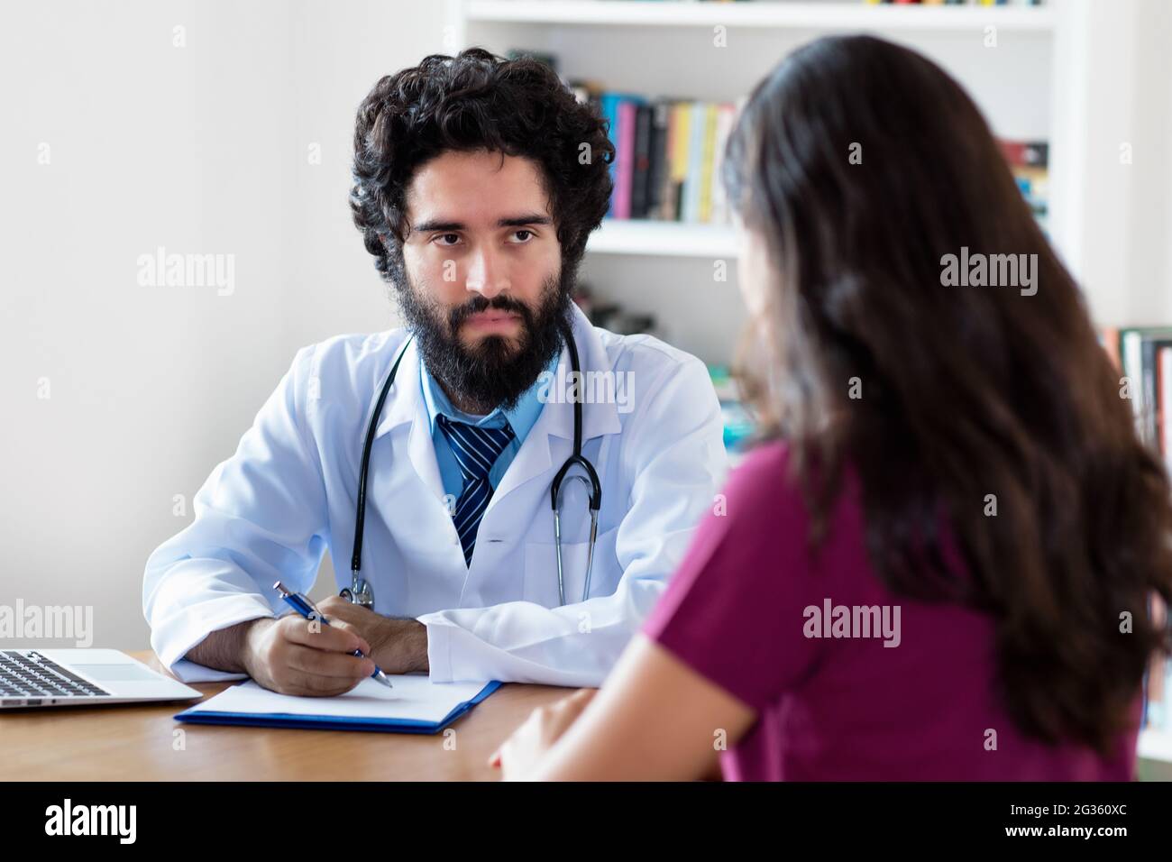 Pakistani male doctor talking to female patient at hospital Stock Photo