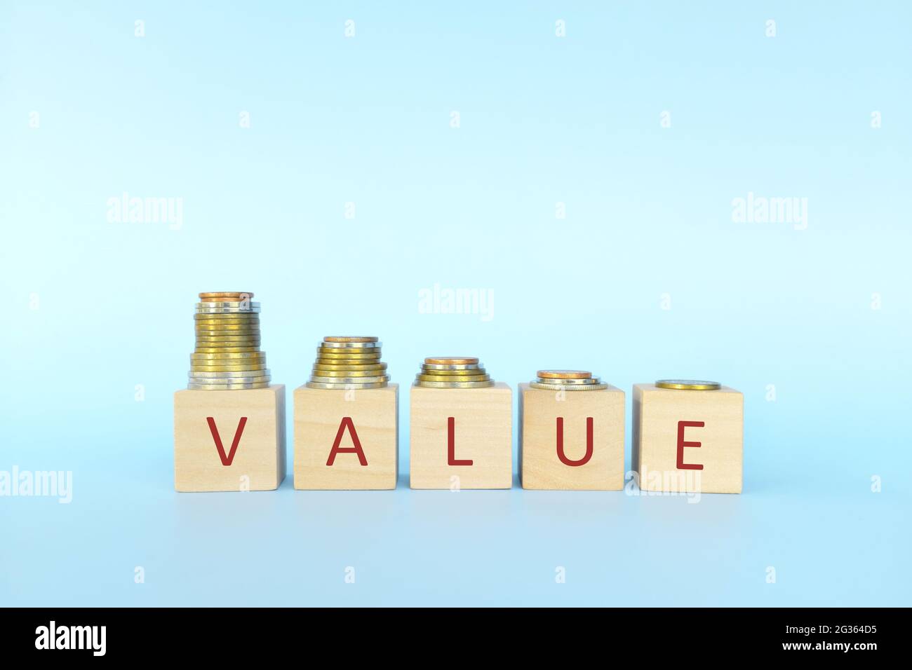 Price devaluation or value depreciation concept. Decreasing stack of coins in wooden blocks with word value. Stock Photo