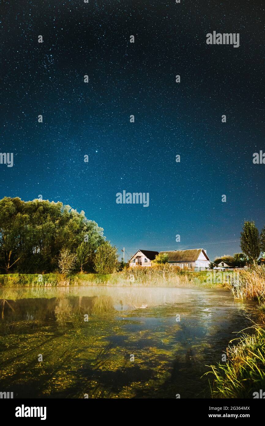 Evaporation Over River Lake Near Houses In Village. Milky Way Galaxy In