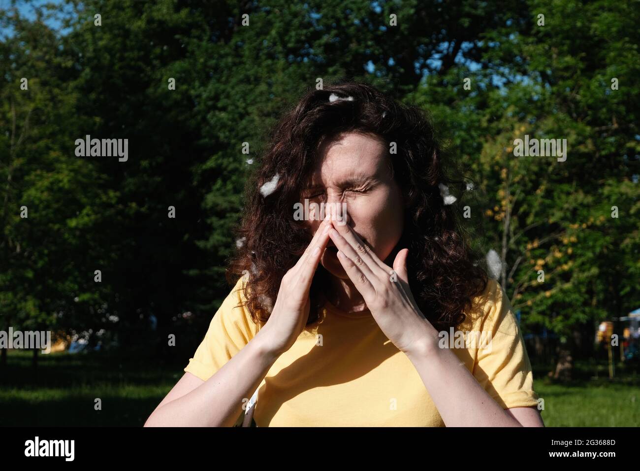 Girl sneezes because of the poplar fluff. Allergic reaction to poplar fluff Stock Photo