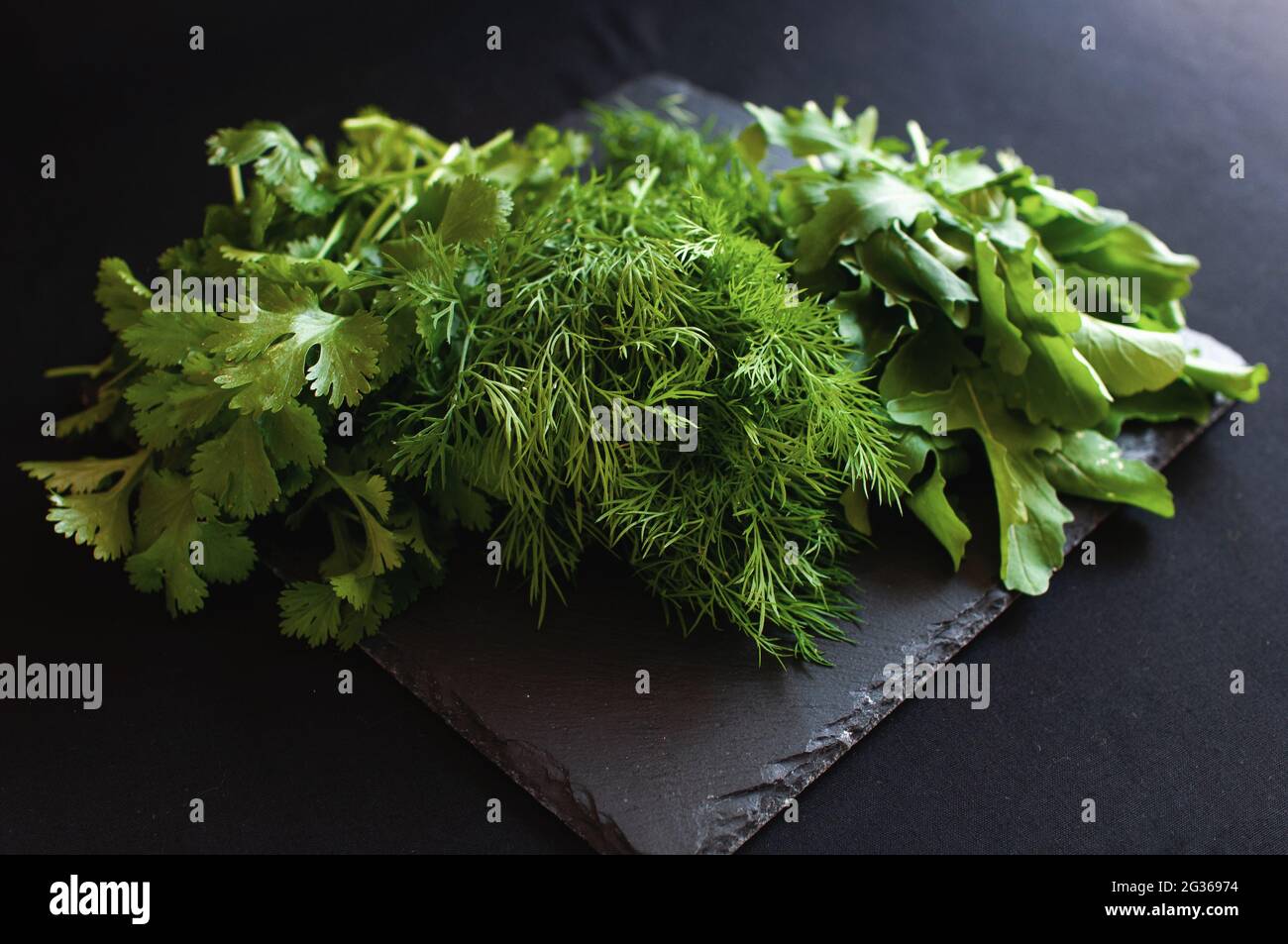 fresh arugula dill and parsley lies on a black board Stock Photo