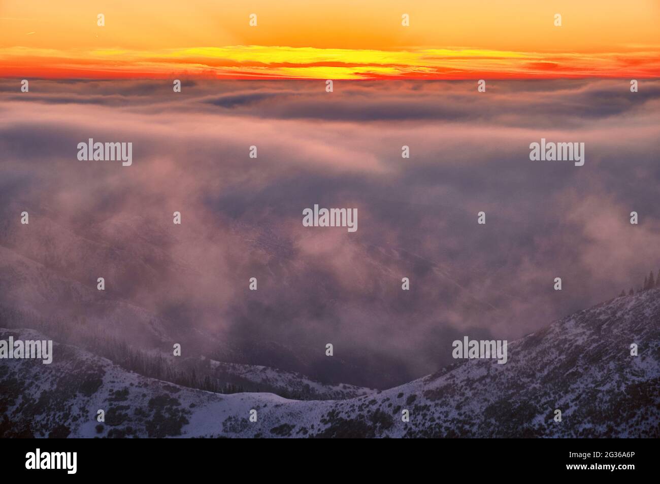 Magical atmosphere of a sunset in the highlands; sunset clouds over snow-capped mountain ridges Stock Photo