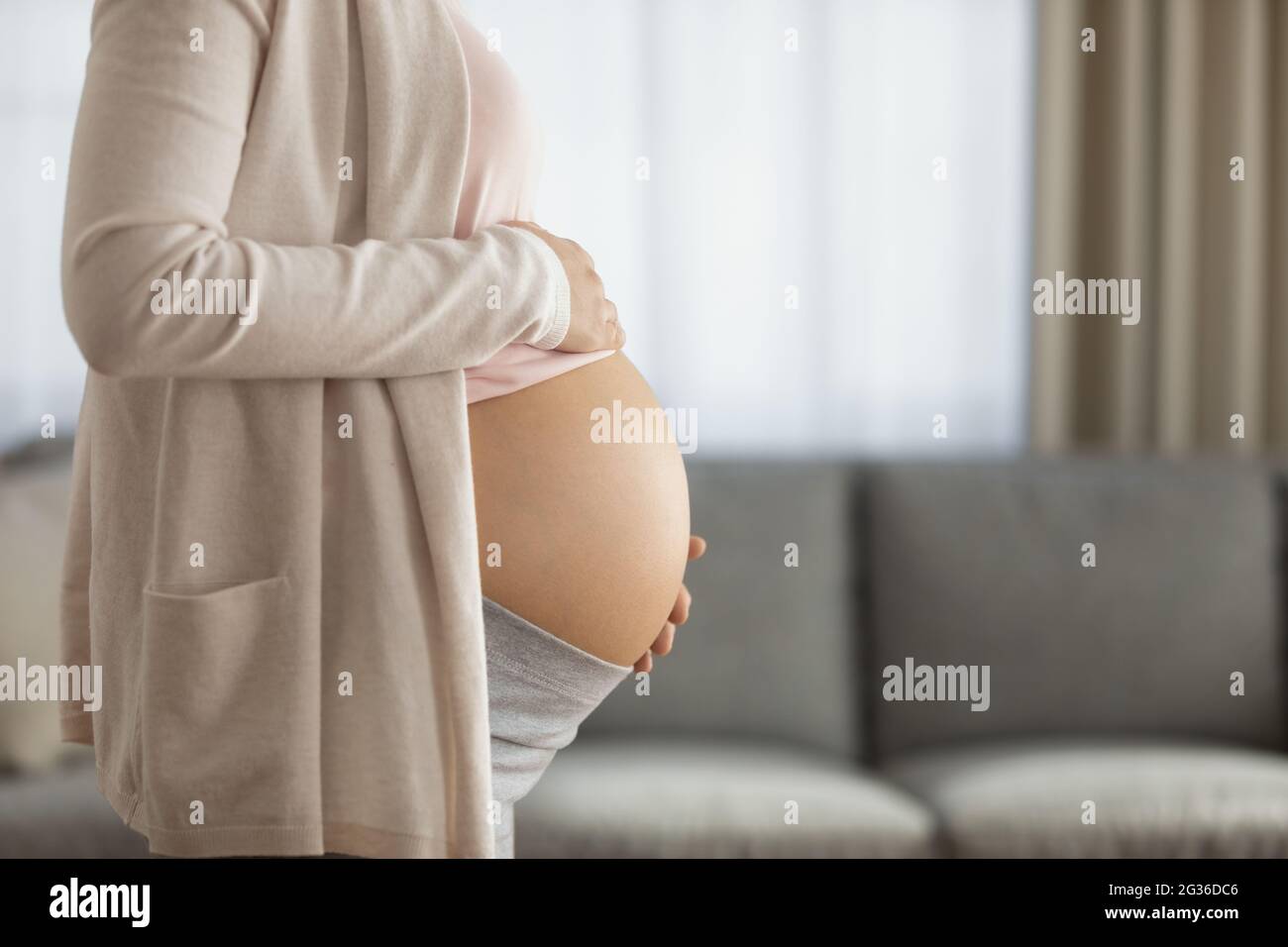 Side view cropped of pregnant woman touching belly, feeling kicks Stock