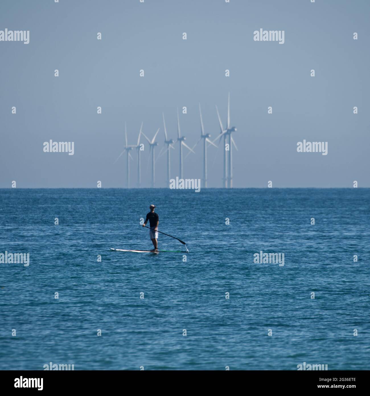 Paddle board by wind turbines Stock Photo