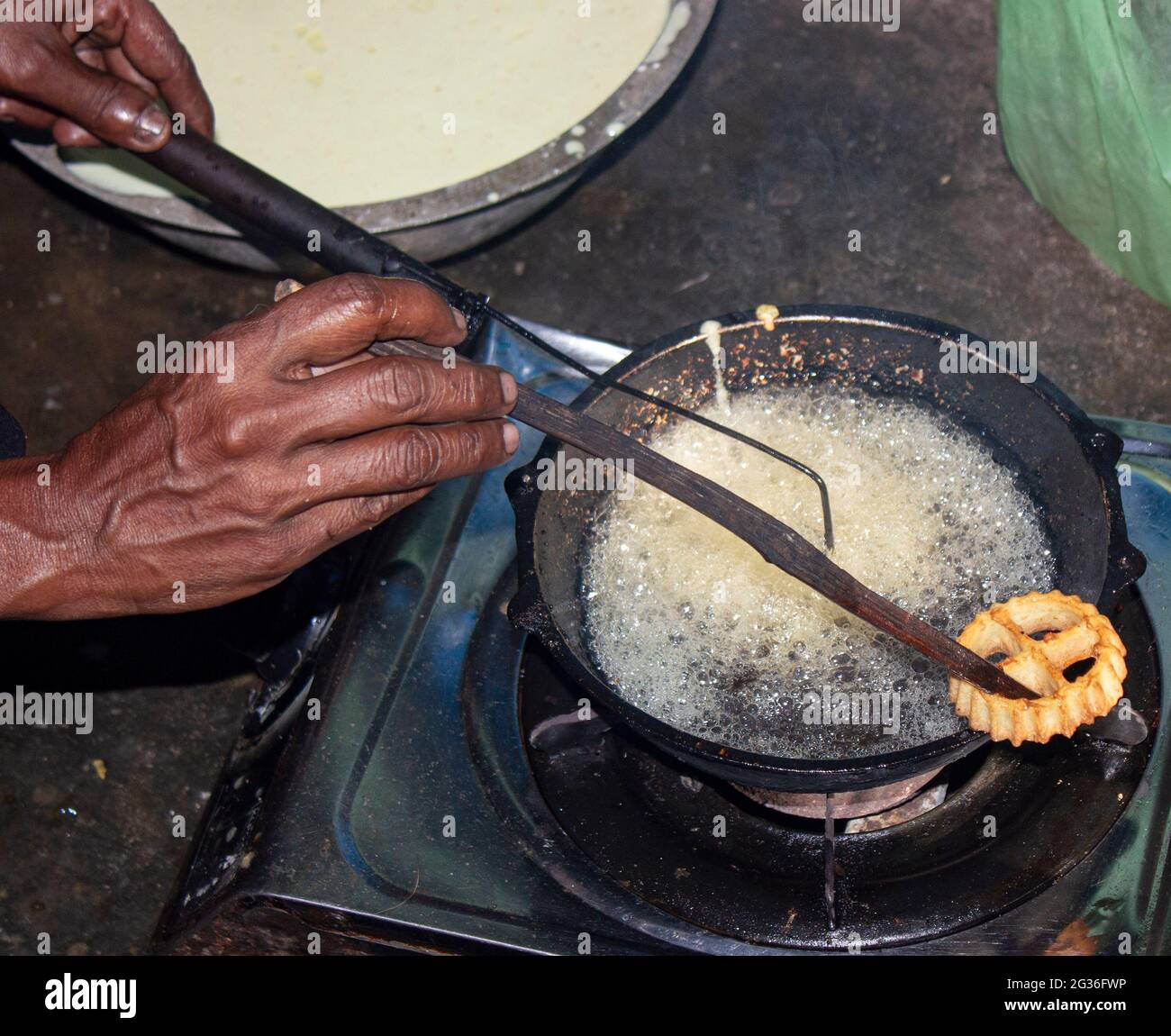Village cooking; village girl cooking; frying sweets; traditional food; frying kokis; making cookies; rosette cookies; frying rosette cookies; Stock Photo