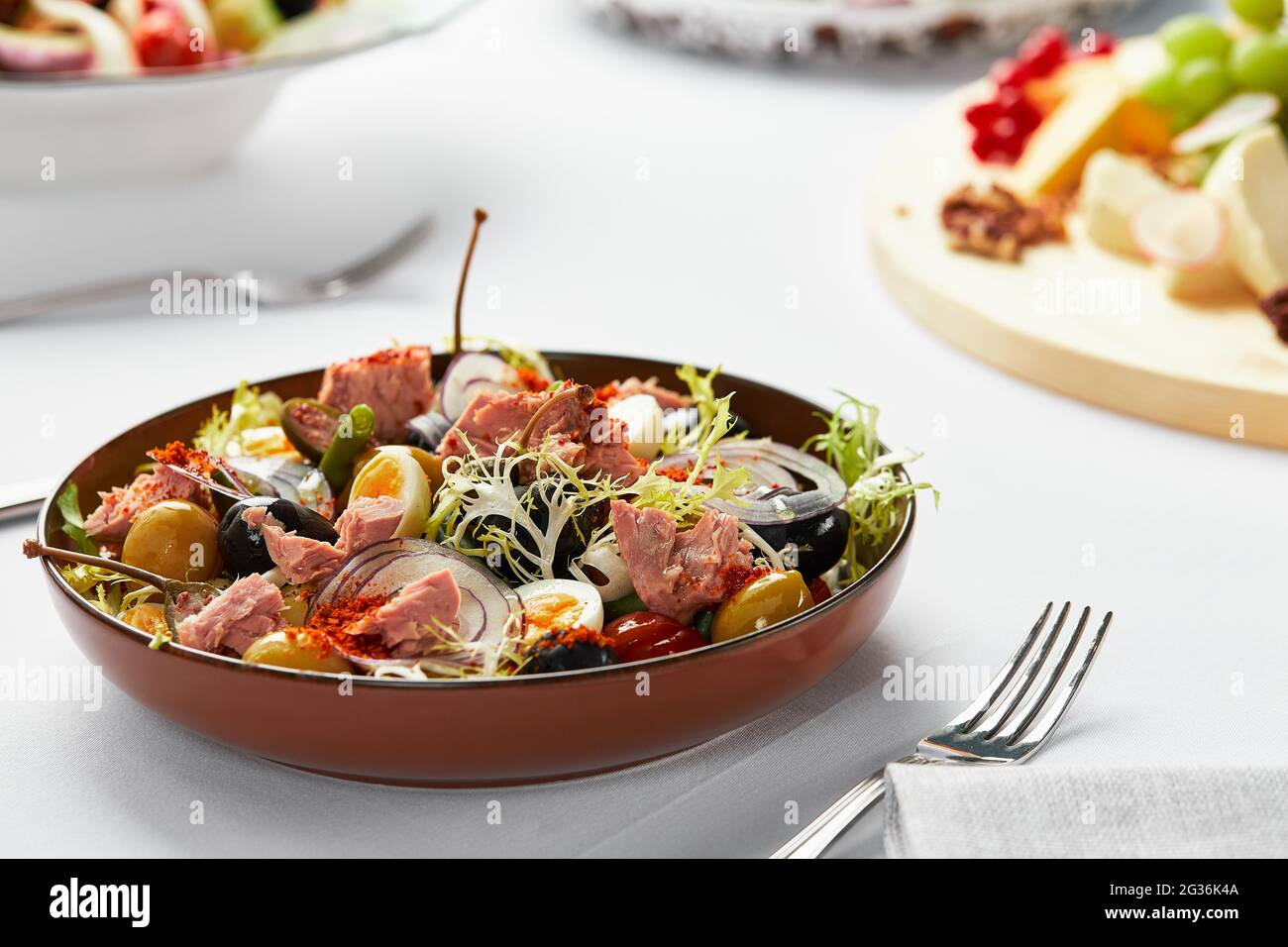 Nicoise salad on the banquet table, classic nicoise salad served by the chef in a craft plate, tuna salad with eggs and olives Stock Photo