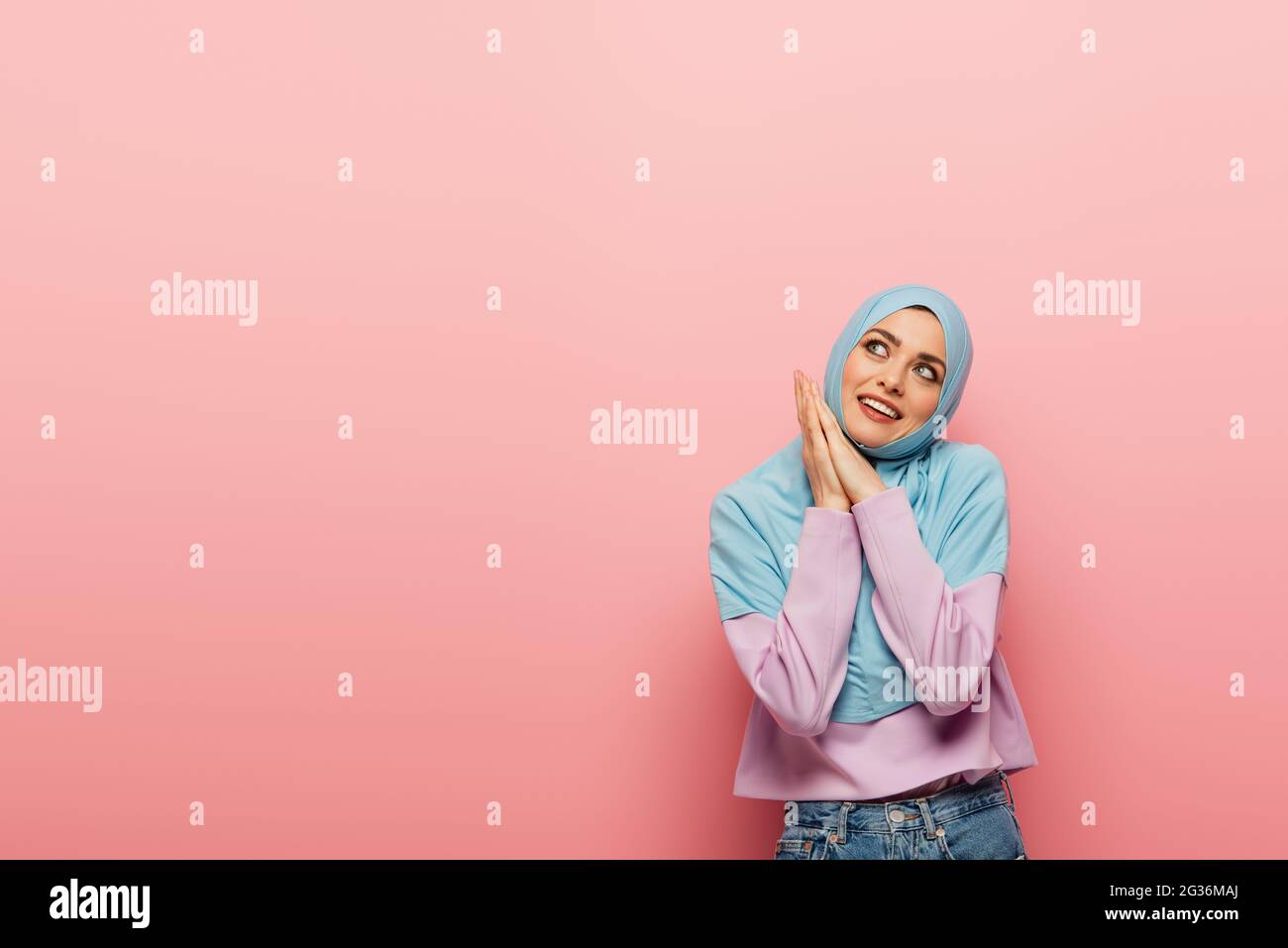 happy muslim woman in blue hijab looking away on pink background Stock ...