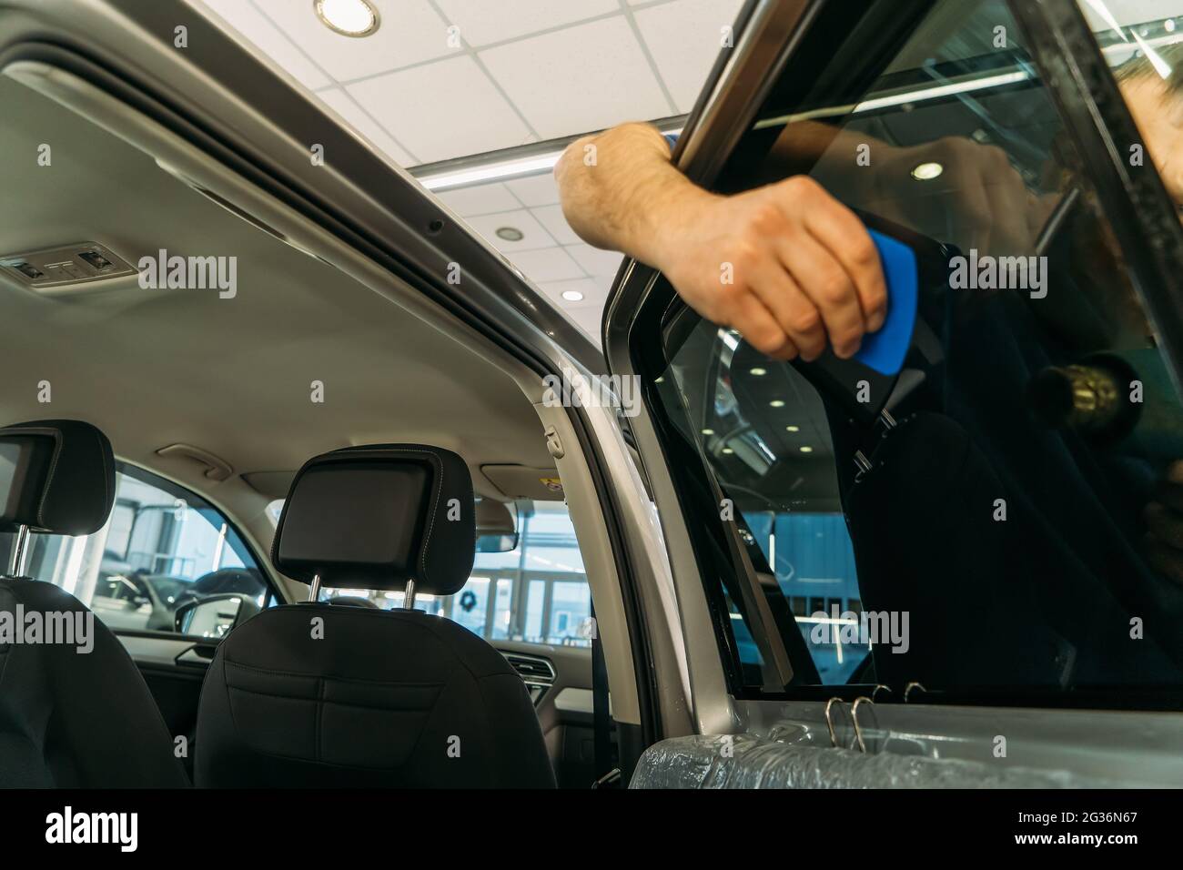 Car window tinting. Process of Installation window tint in Car Detailing Studio Garage by professional detailer. Stock Photo