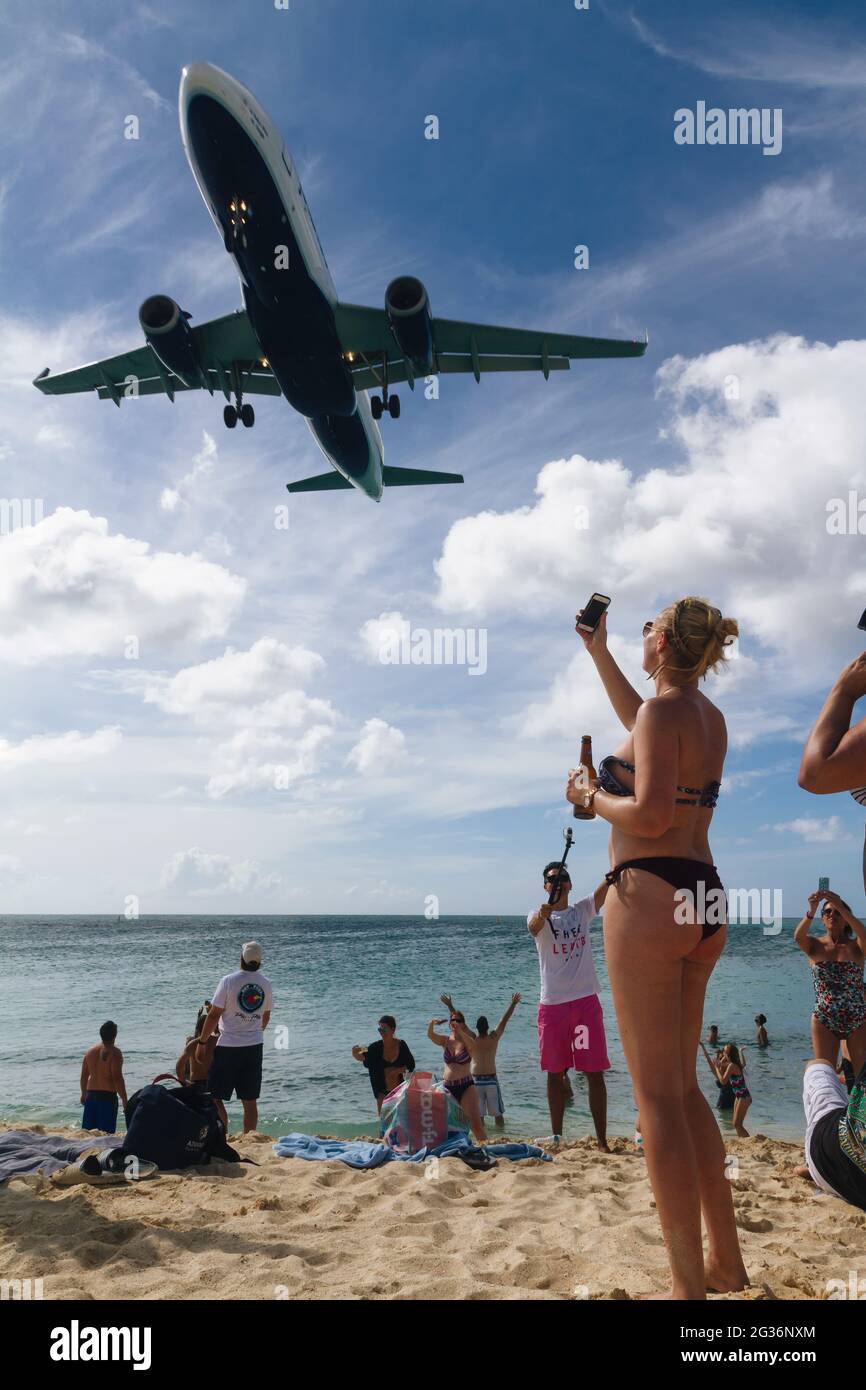 Sint Maarten, Dutch Antilles - December 04, 2015: Tourists watch from the beach as the plane lands at Princess Juliana International Airport in St. Ma Stock Photo