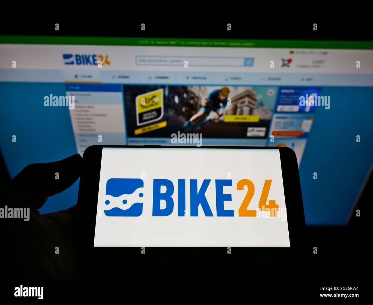 Person holding cellphone with logo of German bicycle e commerce company Bike24 GmbH on screen in front of business webpage. Focus on phone display Stock Photo Alamy