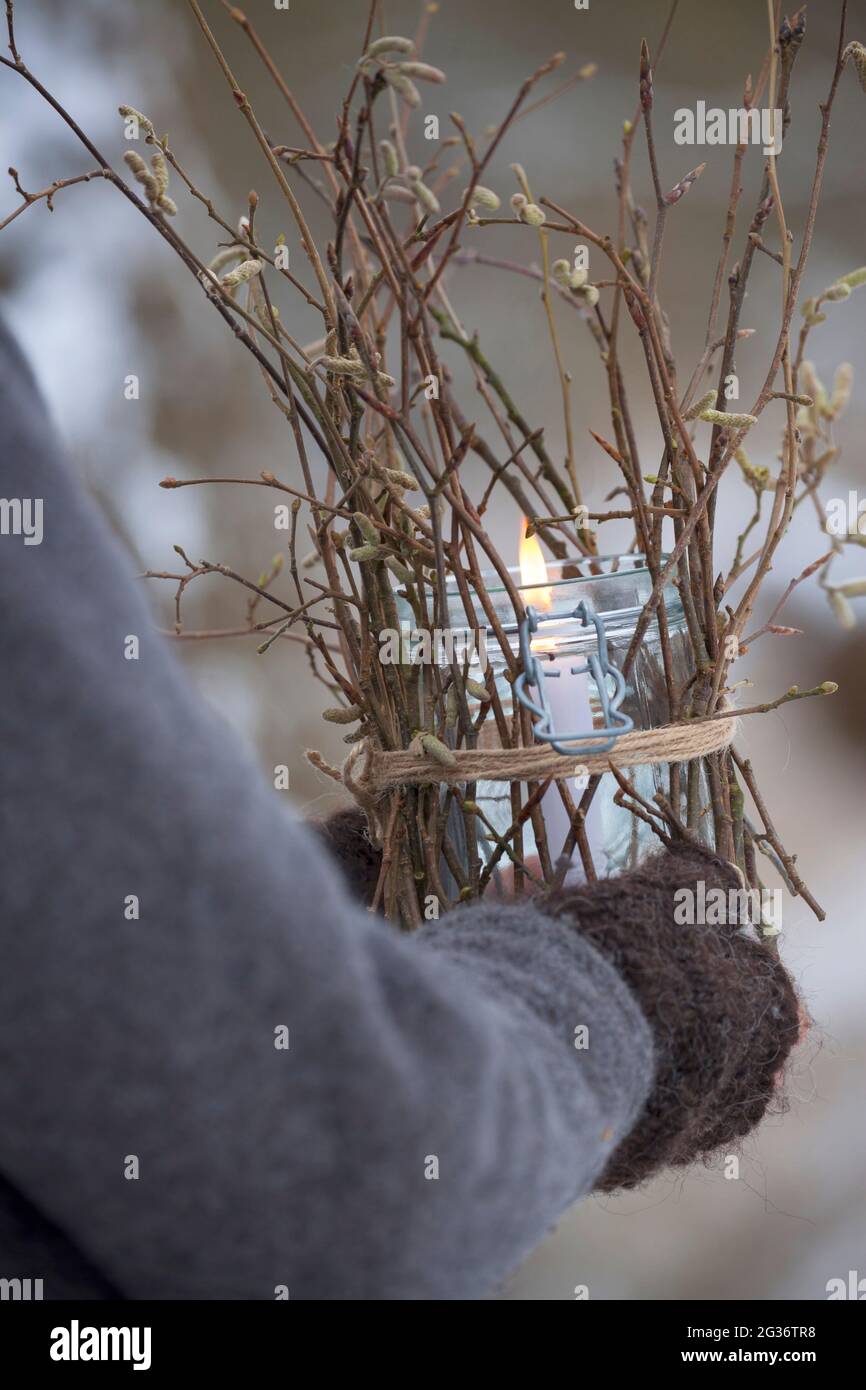 carried lantern, a glass is decorated from the outside with sticks, twigs, twigs. A candle stands and burns in the glass, sheltered from the wind, Stock Photo