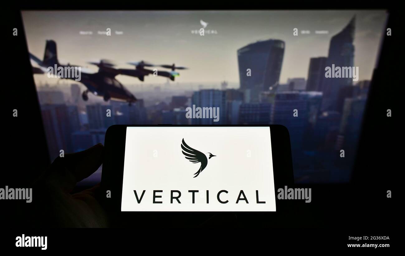 Person holding smartphone with logo of British aircraft company Vertical Aerospace Ltd. on screen in front of website. Focus on phone display. Stock Photo