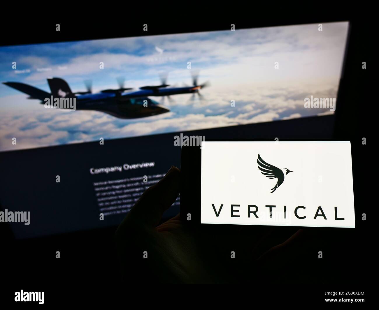 Person holding mobile phone with logo of British aircraft company Vertical Aerospace Ltd. on screen in front of web page. Focus on phone display. Stock Photo