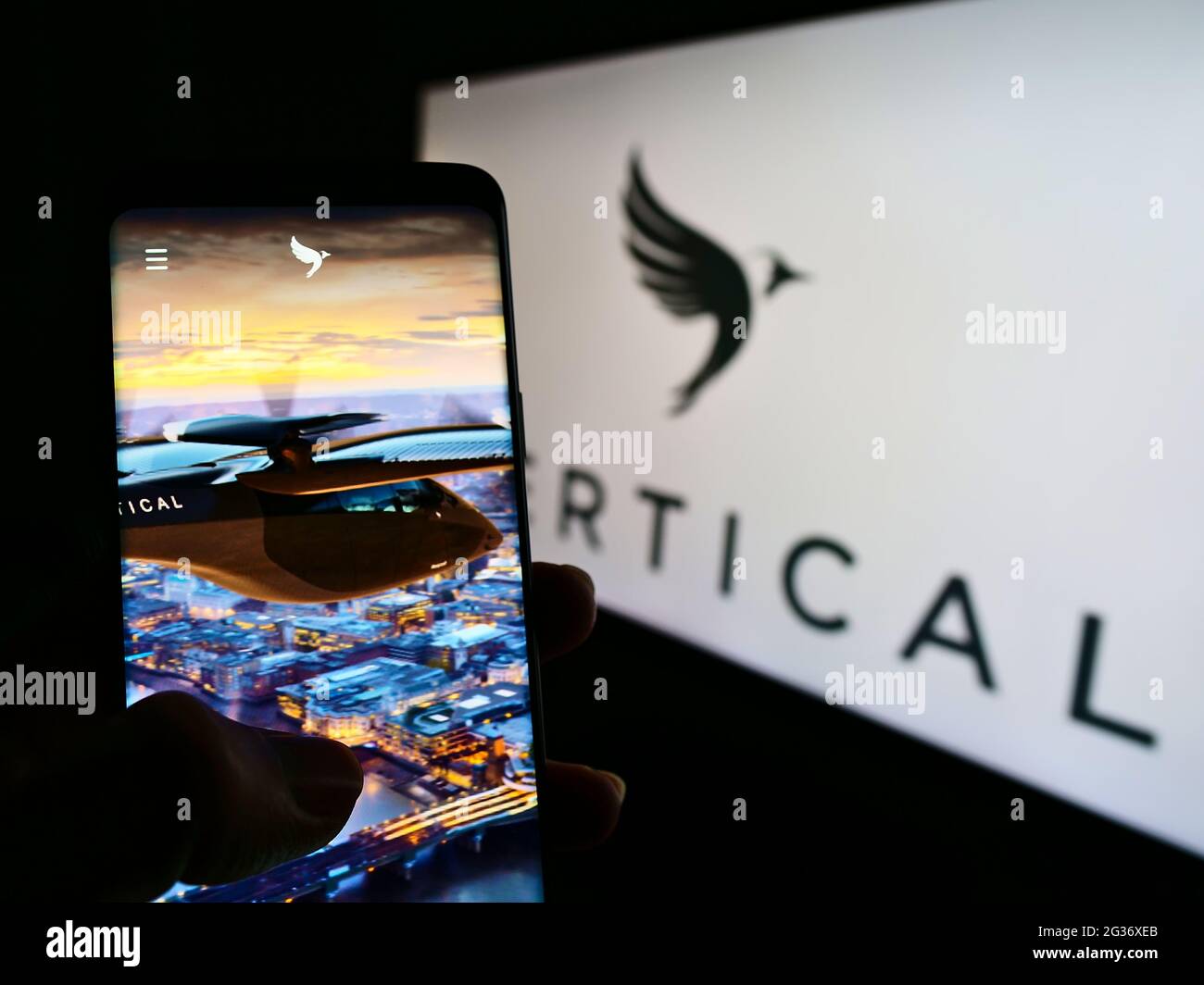 Person holding smartphone with website of British aircraft company Vertical Aerospace Ltd. on screen with logo. Focus on center of phone display. Stock Photo