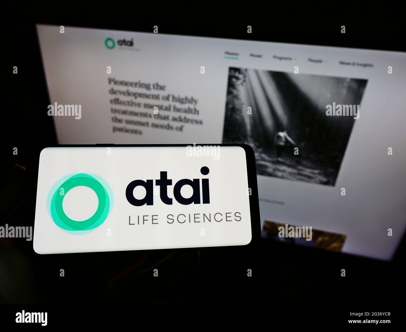 Person holding smartphone with logo of German biotech company ATAI Life Sciences AG on screen in front of website. Focus on phone display. Stock Photo