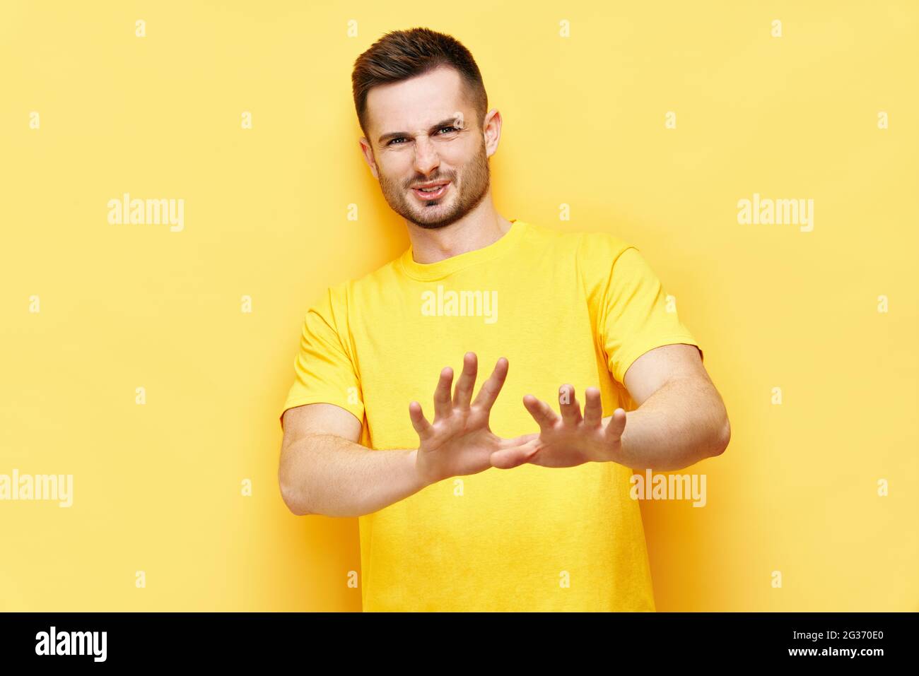 Young displeased man making stop gesture sign say no isolated on yellow background. Negative emotion, facial expression Stock Photo