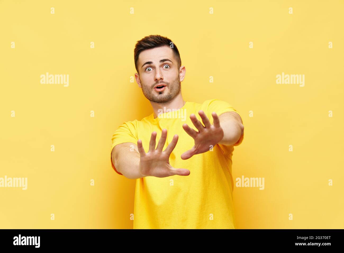 Young displeased man making stop gesture sign say no isolated on yellow background. Negative emotion, facial expression Stock Photo