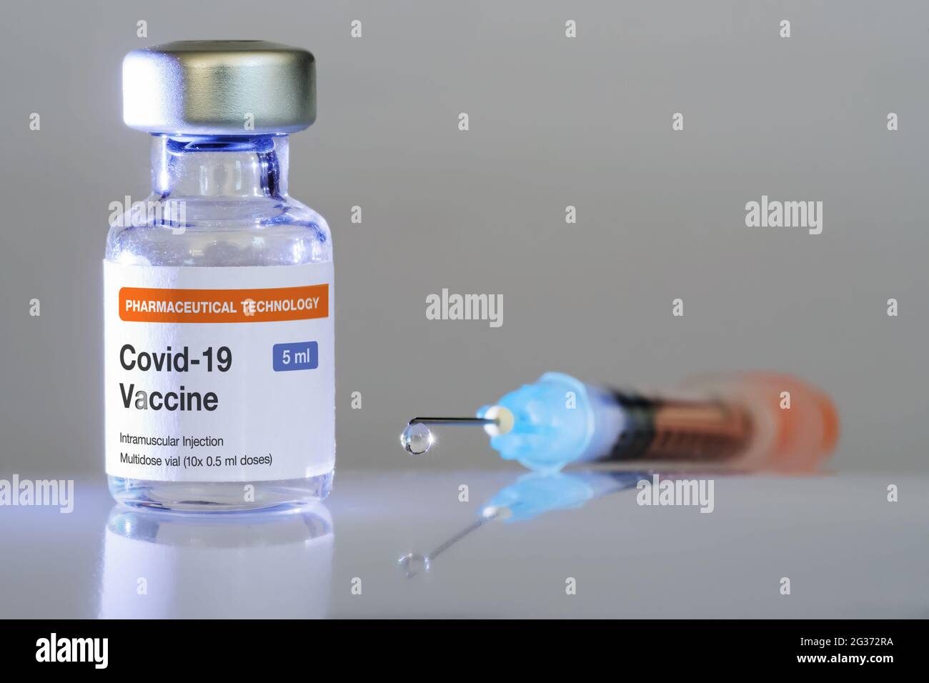 Vial with COVID-19 vaccine and syringe with vaccine droplet hanging at the tip of a needle close-up. Vaccination, Covid-19, pharmaceutical industry an Stock Photo