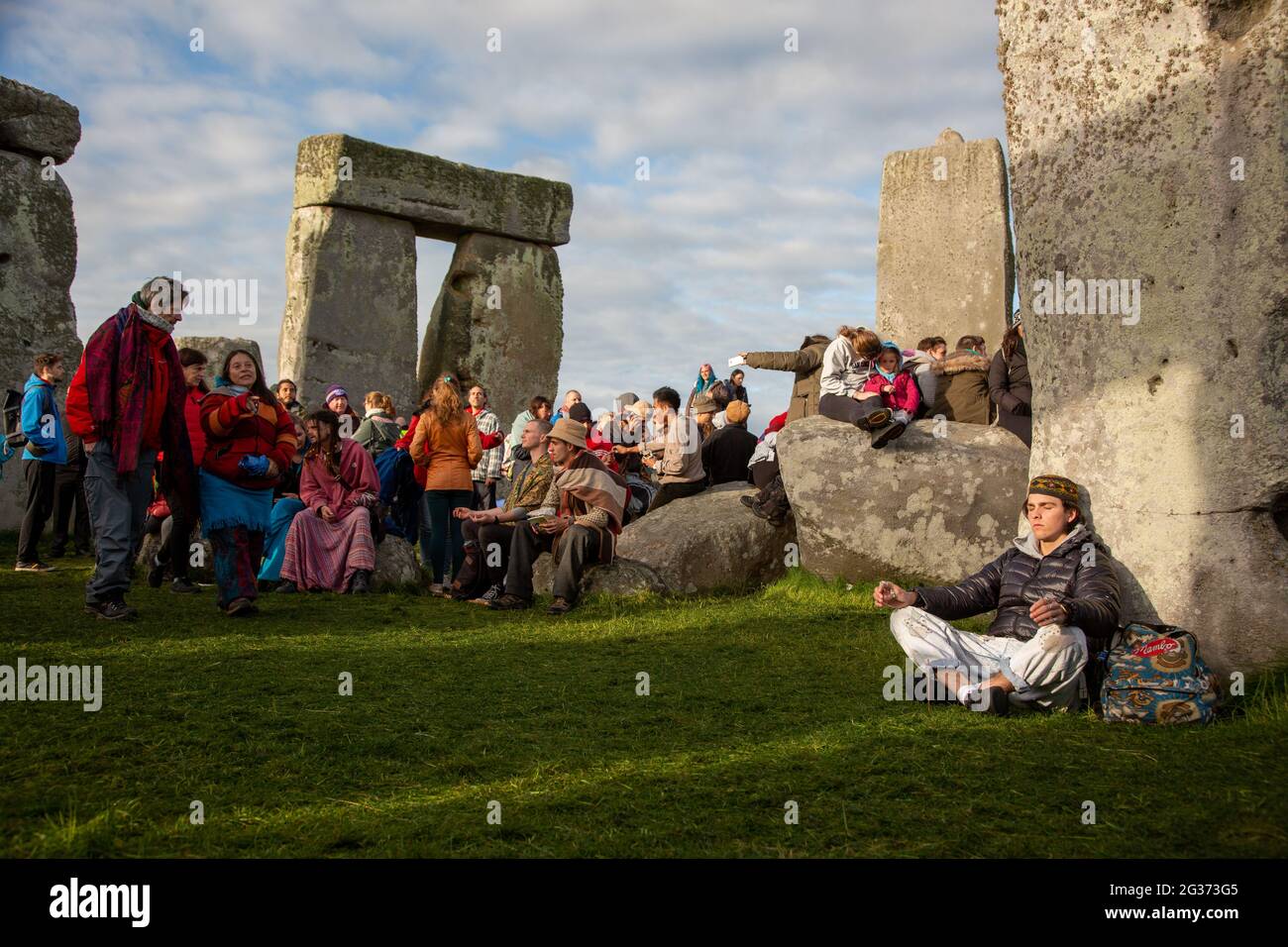 A man meditates by the sacred stones of Stonehenge monument in Wiltshire, UK. --- The 21st of June is the day of the summer solstice. It is the longes Stock Photo