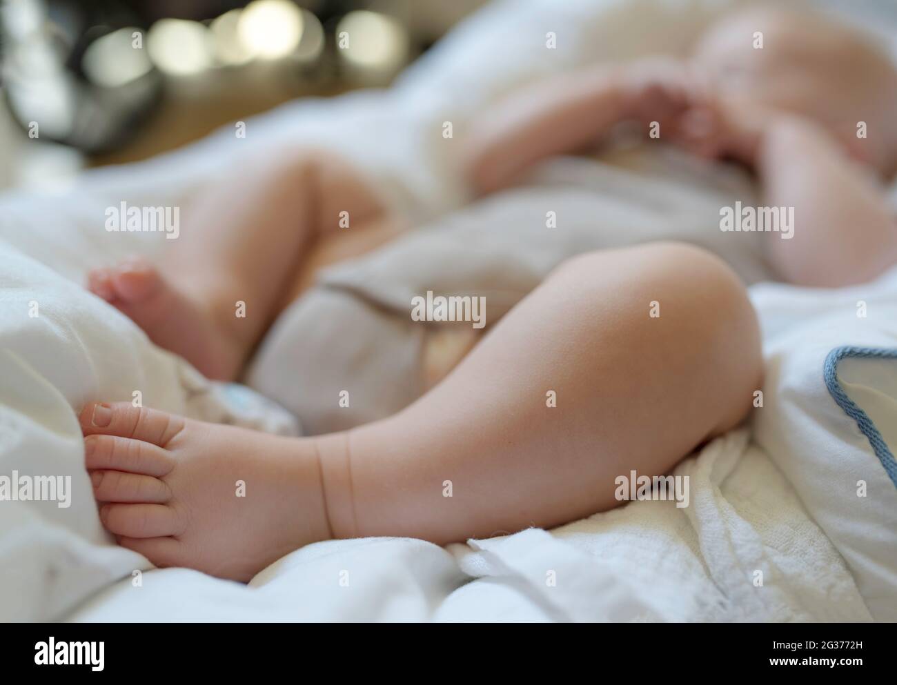 close-up of 3 month old baby sleeping in bodysuit, focus on feet Stock Photo