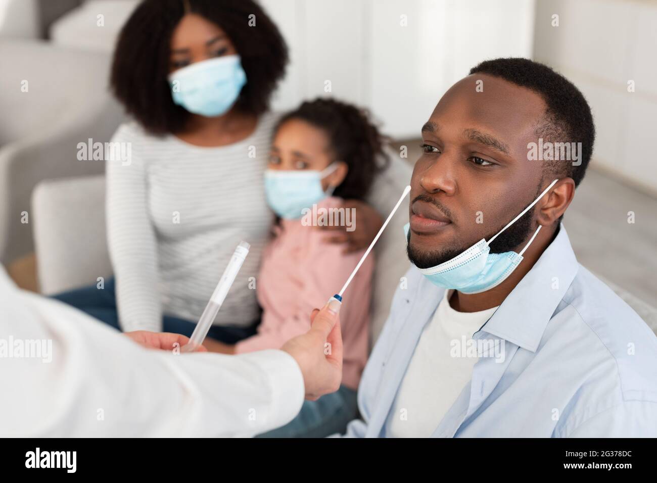 Doctor taking PCR test sample from potentially infected black man Stock Photo