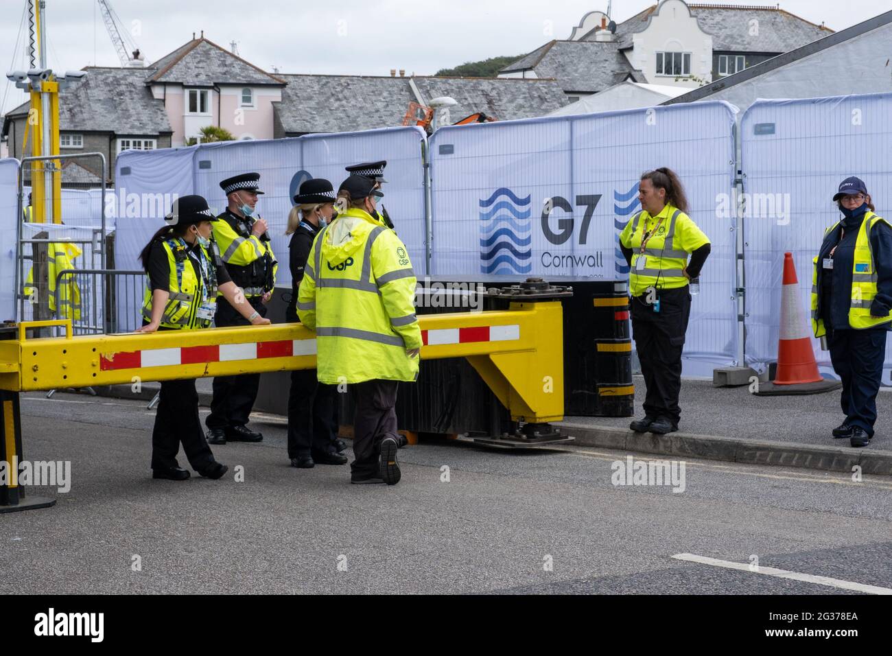 A group of yellow vested police, community police and volunteers beside a barrier to the G7 entrance to the huge news teams area near Falmouth Harbour Stock Photo