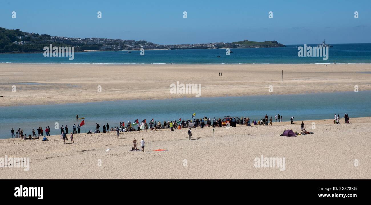 View of peaceful protestors at a distance across Hayle's sandy beaches and sea opposite to Carbis Bay and St Ives where the G7 Summit was taking place Stock Photo