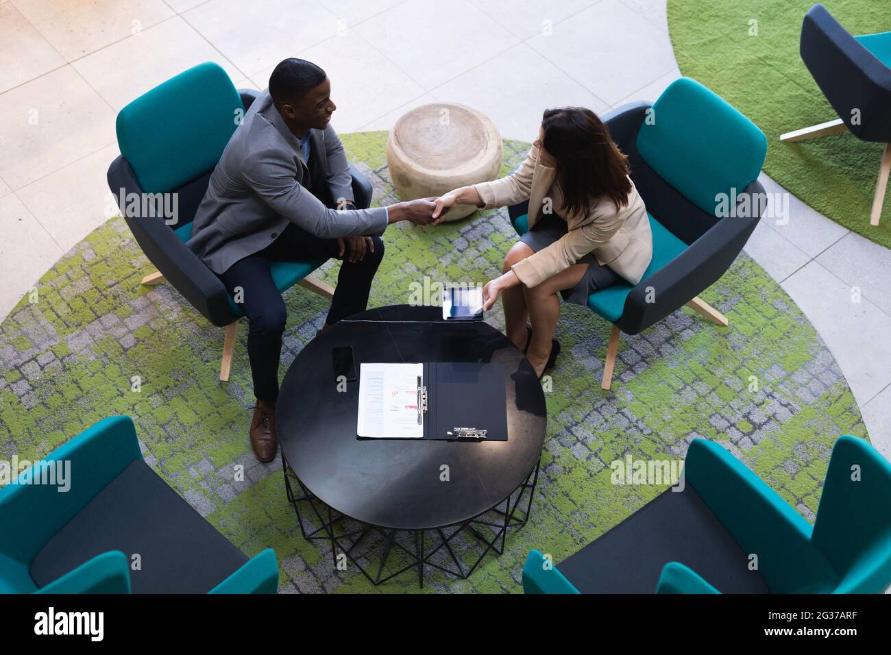 Overhead view of diverse businessman and businesswoman shaking hands at modern office Stock Photo