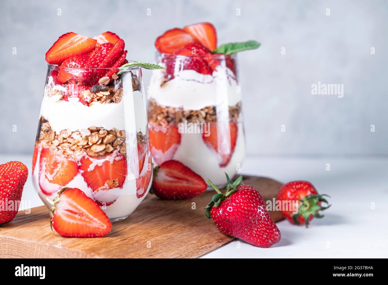 Healthy breakfast of strawberry parfaits made with fresh strawberry, yogurt and muesli in glasses. Stock Photo
