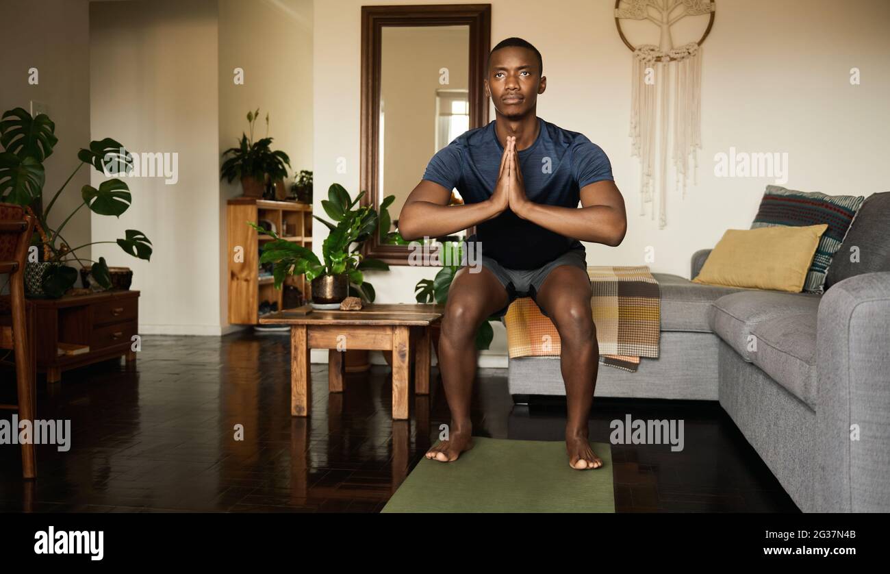 African man in the chair pose while doing yoga at home Stock Photo