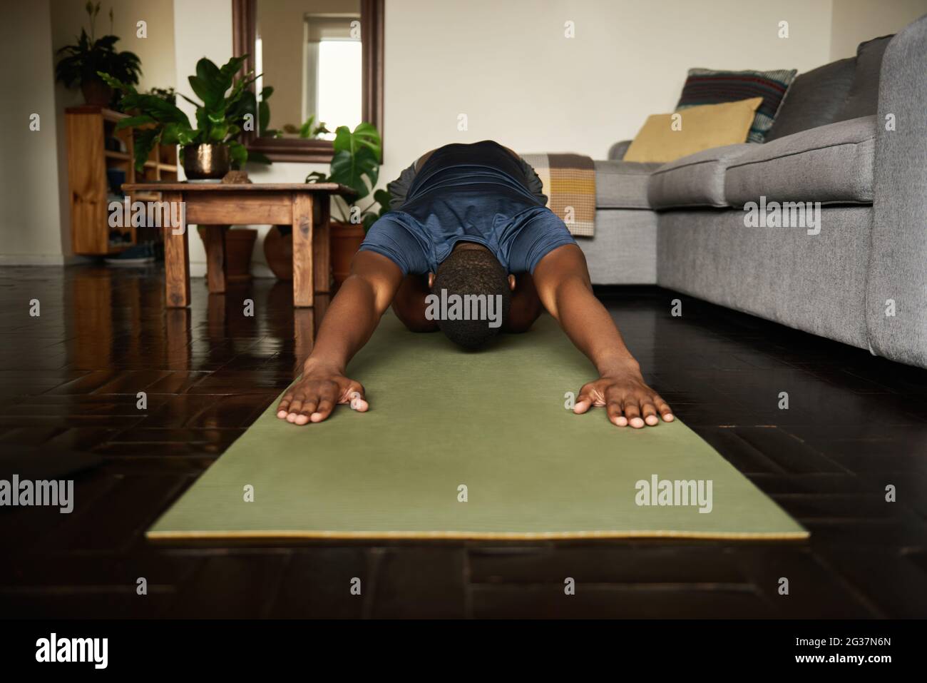Young African man in the child's pose during yoga at home Stock Photo