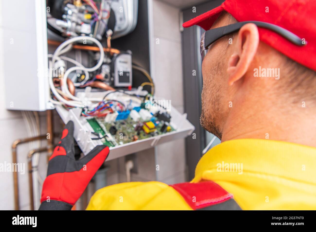 Modern Central Gas Heater Electronics Repair. Caucasian HVAC Technician Looking Inside the