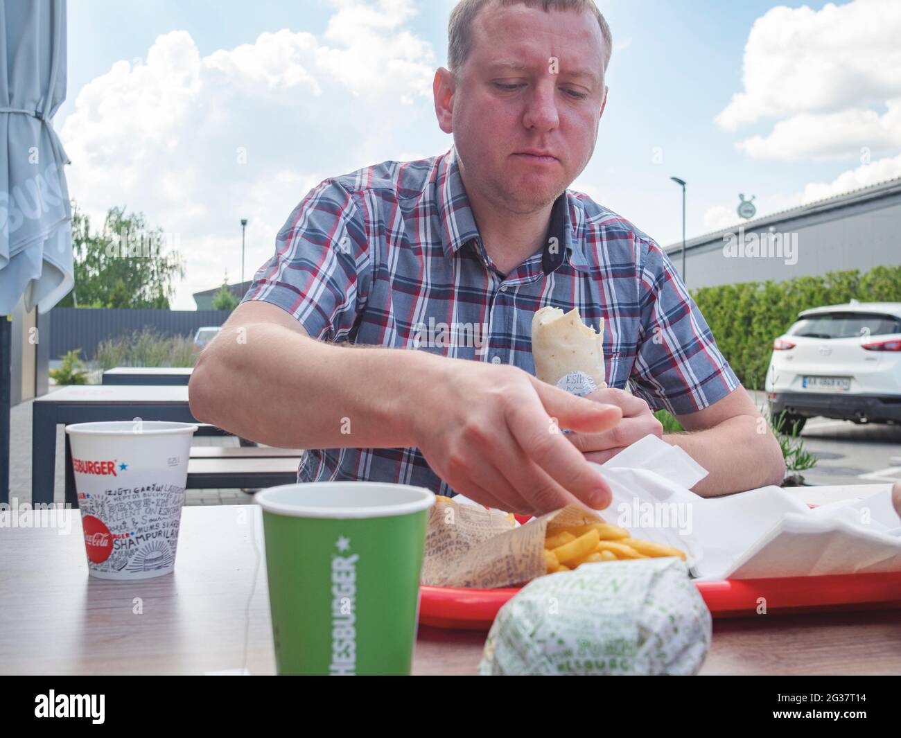 A young man dines at the Hesburger restaurant in the village of Shchasliv on the highway Kiev - Boryspil international airport. The Finnish restaurant chain Hesburger is actively developing in the capital region of Ukraine. Of the five hundred restaurants of this chain, seven operate in Kiev and the region. Stock Photo