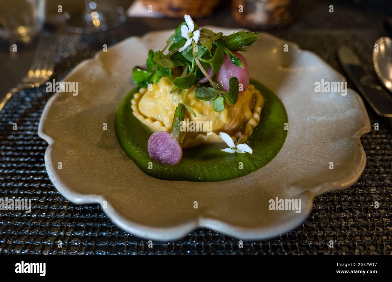 Starter course of ravioli with radishes and lovage puree served at a fine dining restaurant table Stock Photo